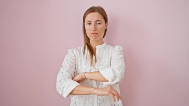 神经质的年轻女人穿着粉色衬衫 站在疑神疑鬼的立场上 双臂交叉在孤立的粉色背景上 不高兴的女性怀疑者的负面表情 — 图库视频影像