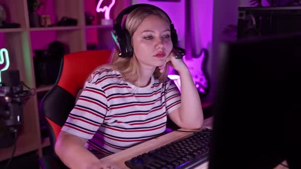 专注的高加索女人深夜在一个有键盘 耳机和霓虹灯的充满活力的房间里玩游戏 — 图库视频影像