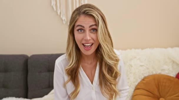 Szczęśliwa Młoda Blondynka Siedząca Salonie Rękami Górze Pochłonięta Ekscytującymi Domowymi — Wideo stockowe