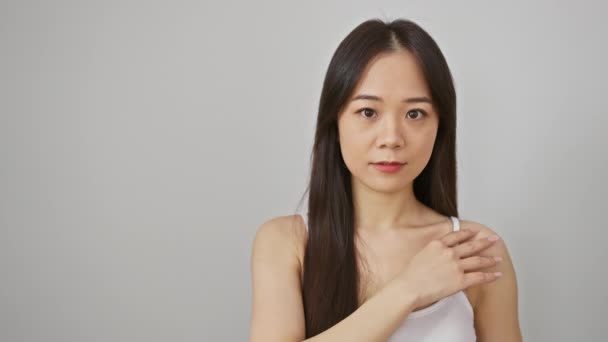 一位有思想的年轻亚洲女人穿着白色的背心 衬托着纯白的背景 显得简朴优雅 — 图库视频影像