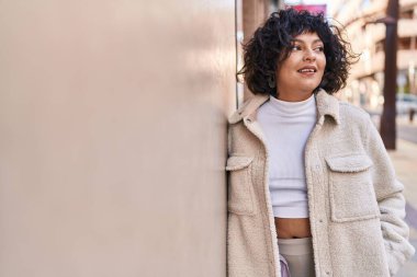 Young beautiful hispanic woman smiling confident looking to the side at street