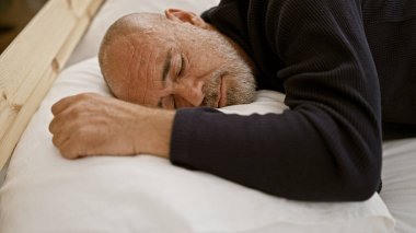 Sakallı, olgun kel bir adam rahat bir yatak odasında huzur içinde uyuyor. Huzur ve istirahat tasvir ediyor..