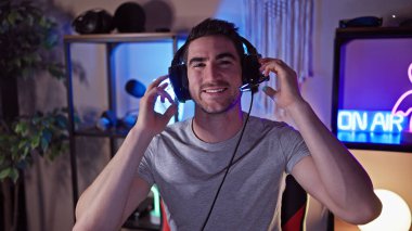 Oyun odasında kulaklık takan genç İspanyol bir adam ve gece yarısı 