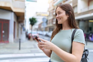 Sokakta akıllı telefon kullanan kendine güvenen güzel bir kadın.