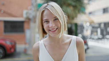 Sokakta kendine güvenen genç sarışın kadın gülümsüyor