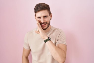 Sakallı İspanyol bir adam pembe arka planda duruyor. Ağzı açık, gizli dedikodular yayıyor, kötü niyetli konuşmalar fısıldıyor. 