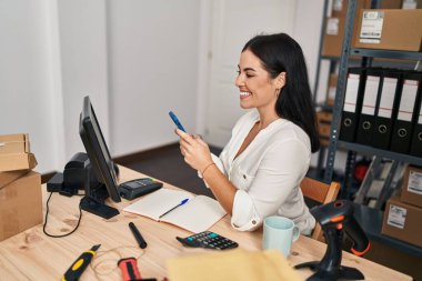 Genç, güzel, İspanyol bir kadın. İş kadını. Ofiste akıllı telefon kullanıyor.