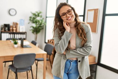 Genç, güzel, İspanyol bir iş adamı. Kendine güler yüzlü. Ofiste kollarını kavuşturmuş duruyor.