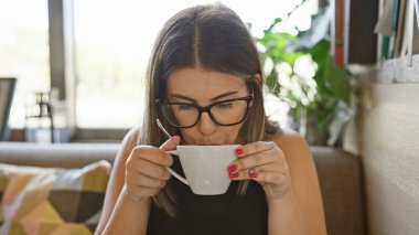 Kafe masasında kahve içen genç bir İspanyol kadın.