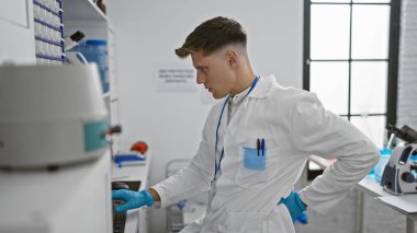 Laboratuvarda bilgisayarında ciddi şekilde yazı yazan çekici beyaz erkek bilim adamı, bir sırt ağrısı salgınıyla karşı karşıya. Araştırma hayatının acımasız gerçeği..