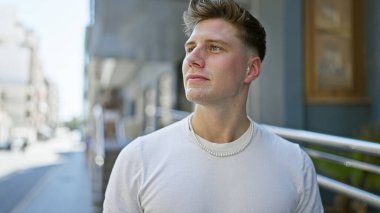 Genç, yakışıklı, beyaz, sakin ama ciddi bir yüz ifadesi sergiliyor, açık havada güneşli bir havada dikilirken yan tarafa bakıyor. Sokak modası şehir ve havalı yaşam tarzını gözler önüne seriyor.