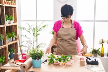 Middle age chinese woman florist make bouquet of flowers at flower shop