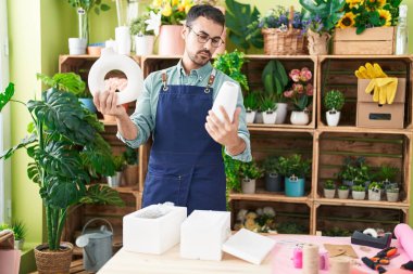 Çiçekçide saksı tutan İspanyol bir çiçekçi.