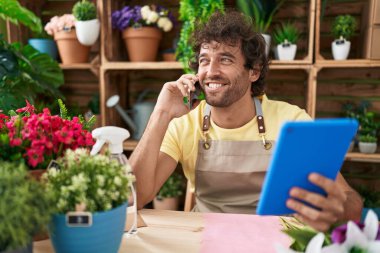 Çiçekçide dokunmatik ped kullanarak konuşan genç İspanyol çiçekçi.