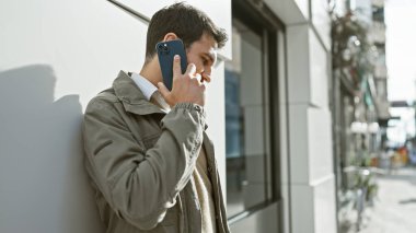 Latin kökenli genç bir adam şehir sokağında dikilirken telefonla konuşuyor. Sıradan ve bağlantılı bir yaşam tarzını canlandırıyor..