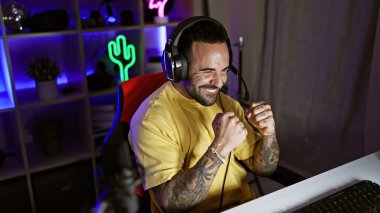 İspanyol adam neon ışıklarıyla karanlık bir odada oynarken gülüyor.