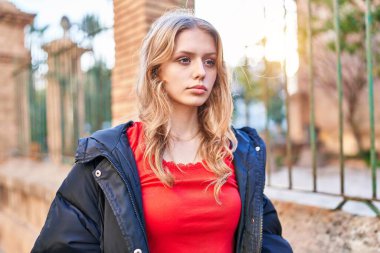 Sokakta ciddi bir ifadeyle yan tarafa bakan genç sarışın kadın.