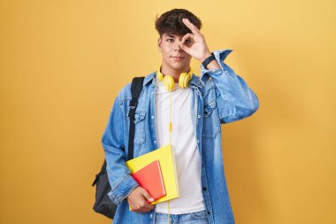 İspanyol ergen öğrenci çantası takıyor ve kitap tutuyor. El hareketleriyle gülümsüyor, gözleriyle mutlu yüzlere bakıyor.. 