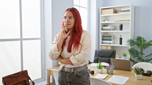 Beautiful young redhead business woman working in office, a portrait of elegance, confidence, and success, thinking and doubting business ideas