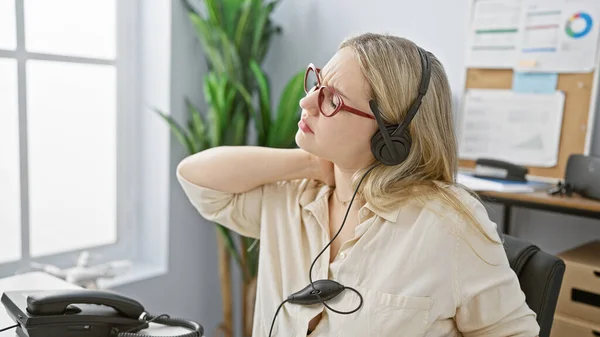 Pained Young Woman Headphones Touching Her Neck Modern Office Setting — Stock Photo, Image