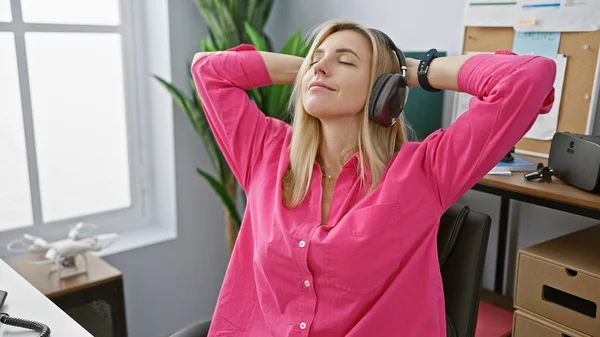 Rahatlamış Genç Bir Kadın Parlak Bir Ofis Ortamında Kulaklıklarla Müzik — Stok fotoğraf