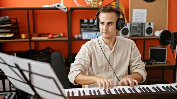 一个英俊的年轻人在现代录音室里录制音乐 弹奏键盘 — 图库照片