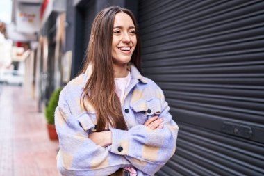 Sokakta kollarını kavuşturmuş genç, güzel İspanyol bir kadın.