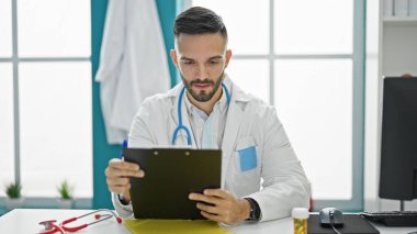 Genç İspanyol doktor klinikteki panoda dokümanları okuyor.