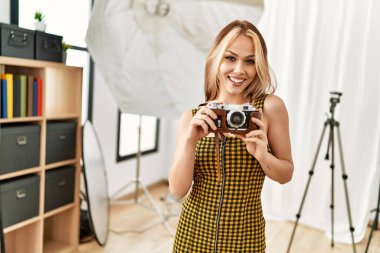 Beyaz kadın fotoğrafçı elinde klasik fotoğraf stüdyosu tutuyor.