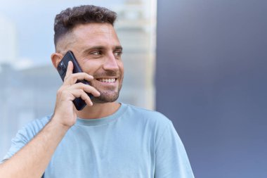 Genç İspanyol adam gülümsüyor. Kendine güveniyor. Sokakta akıllı telefondan konuşuyor.