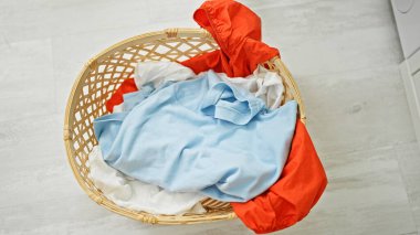 Afrika kökenli Amerikalı kadın çamaşırhanede çamaşır sepetine kıyafet atıyor.