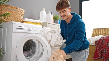 Çamaşır odasında kendine güvenen genç İspanyol adam gülümsüyor.