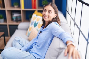 Evdeki kanepede oturan kendine güvenen güzel İspanyol kadın.