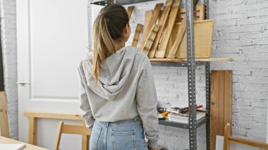 İspanyol kadın marangozluk atölyesinde ahşap kalaslar seçiyor, yaratıcı bir diy projesini canlandırıyor..