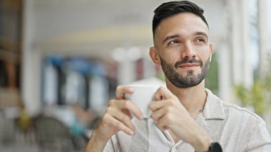 Genç İspanyol gülen adam kahvecinin terasında kendinden emin bir şekilde kahve içiyor.