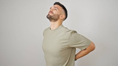 Sırt ağrısı yüzünden acı çeken İspanyol genç adam izole edilmiş beyaz arka planda duruyor.