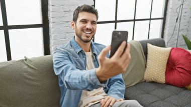 Yakışıklı İspanyol adam modern bir apartman dairesinde selfie çekiyor..