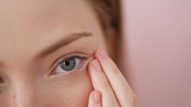 Sarışın genç bir kadın. Koyu bir çember çiziyor. İzole edilmiş pembe arka planı var.