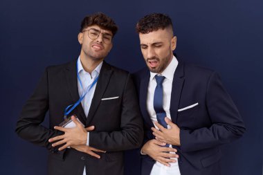 İki İspanyol iş adamı midesi üstünde iş kıyafetleri giyiyorlar çünkü hazımsızlık ve acı veren hastalıklar yüzünden kendilerini kötü hissediyorlar. Ağrı kavramı. 