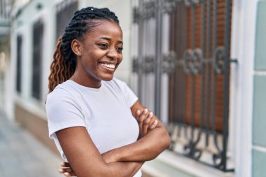 Sokakta kollarını kavuşturmuş Afro-Amerikalı bir kadın.