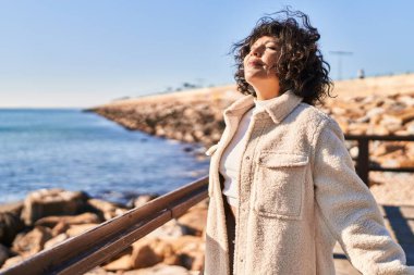 Genç ve güzel İspanyol kadın deniz kenarında gözleri kapalı nefes alıyor.