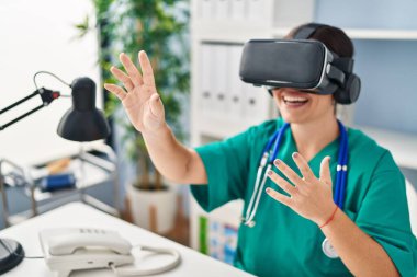 Genç, güzel İspanyol kadın doktor klinikte sanal gerçeklik gözlüğü kullanıyor.