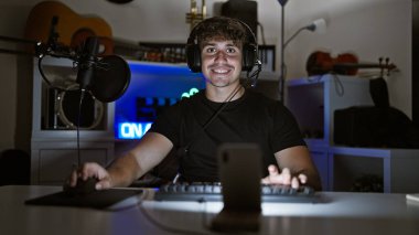 Çekici genç İspanyol bir adam, karizmatik bir oyuncu, gece boyunca rahat oyun odasında sanal bir oyun oynuyor, gülümsüyor ve video üzerinden sohbet ediyor..