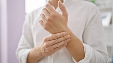 Beyaz adam somurtuyor, bilek ağrısı çekiyor, tuhaf oturma odasında tek başına duruyor, el yaralanmalarıyla gerçek mücadeleyi betimliyor..