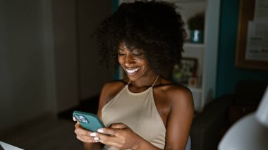 Ofiste çalışan Afrikalı Amerikalı iş kadını akıllı telefon kullanıyor.