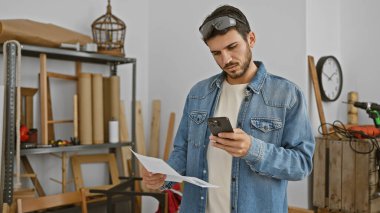 Atölyedeki İspanyol adam elinde telefon ve kağıt tutuyordu.