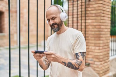 Sokakta video oyunu oynayan genç kel adam.