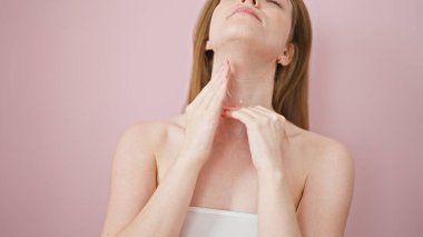 Genç sarışın kadın gülümsüyor kendine güvenen enseye sürdüğü losyonla soyutlanmış pembe arka plan