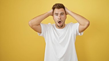 Sarı duvara karşı sakallı, şaşkın ve şaşkın bir genç adam..