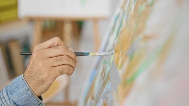 Parlak bir sanat stüdyosundaki tuvale resim yapan yaratıcı bir adamın yakın çekimi.